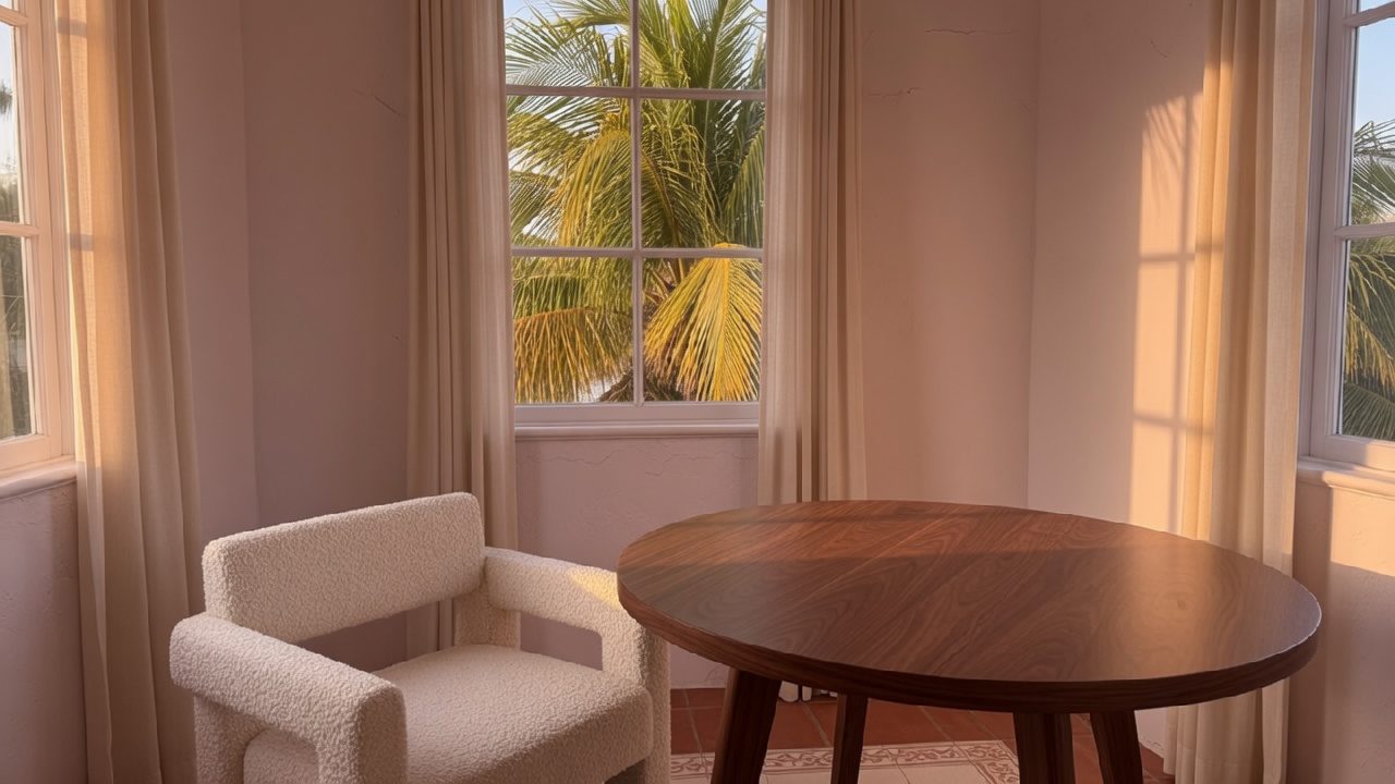 A quiet consultation room with a walnut table, a cream chair, and palms outside.