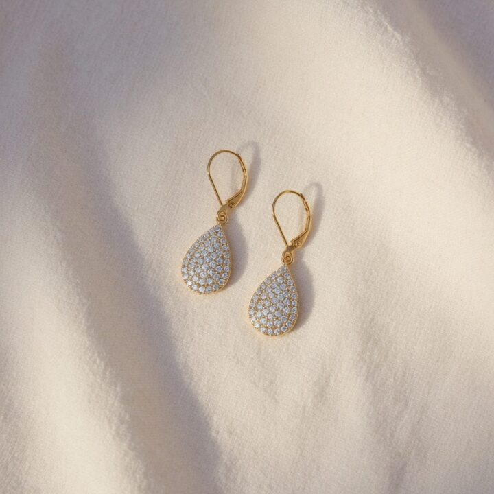 A pair of pavé diamond drop earrings, photographed on cream linen.